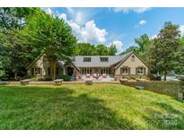 Expansive backyard with a lush lawn, mature trees, and a charming stone patio and fountain at 4531 Montibello Dr, Charlotte, NC 28226