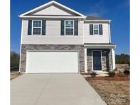 Two-story home featuring gray siding, stone accents, a white garage door, and a dark front door at 1063 Horizon Ln, Chester, SC 29706