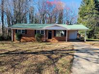 Charming brick home with green metal roof, covered parking, and well-maintained lawn in a quiet neighborhood at 111 Dove Cir, Statesville, NC 28625
