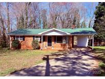 Charming brick home with a green metal roof, a covered carport, and a well-kept front yard at 111 Dove Cir, Statesville, NC 28625