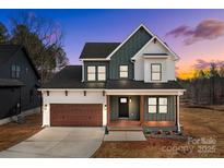 A charming two-story home with a covered porch, a 2 car garage and professional landscaping at 127 Mills Garden Rd, Statesville, NC 28625
