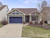 Charming home featuring a blue garage door, inviting porch, and well-maintained landscaping at 131 Chimney Rock Ct, Denver, NC 28037