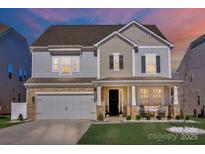 Elegant two-story home with stone accents, a two-car garage, and a charming porch highlighted by evening light at 187 Tetcott St, Mooresville, NC 28115