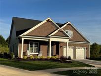 Charming home with a two-car garage, brown shingles, and a inviting front porch with chairs at 19031 Brandon James Dr, Cornelius, NC 28031
