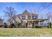 Charming brick home featuring a welcoming front porch and manicured landscaping at 2689 Wingrave Nw St, Concord, NC 28027