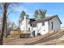 View of the back of the white brick home and wood deck under a clear blue sky at 301 Dollar Cir, Charlotte, NC 28270