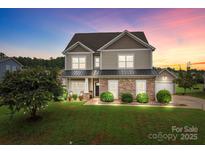 Charming two-story home boasts stone accents, a manicured lawn, and a welcoming front porch with dusk lighting at 3173 Delaware Dr, Denver, NC 28037