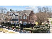 Charming brick townhome featuring manicured landscaping and a white picket fence at 6057 Creft Cir, Indian Trail, NC 28079