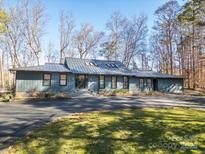 Charming single story home with black metal roof, attractive landscaping, and a spacious front yard at 6108 Phyliss Ln, Mint Hill, NC 28227