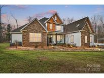 Charming two-story home with stone accents, a covered porch, and a well-manicured lawn at 10000 Blossom Dr, Concord, NC 28025