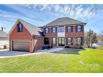 Charming brick two-story home featuring a manicured lawn, attached garage and a cozy outdoor patio seating area at 126 Anchor Ln, Troutman, NC 28166