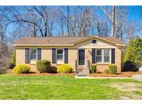 Charming one-story brick home featuring a well-manicured lawn and complementing shrubs at 1438 Plumstead Rd, Charlotte, NC 28216