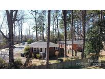 Charming brick home with a cozy front porch surrounded by mature trees and a picket fence at 1738 Matheson Ave, Charlotte, NC 28205