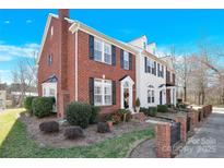Charming red brick and white siding townhome with black shutters and manicured landscaping under a blue sky at 17614 Delmas Dr, Cornelius, NC 28031