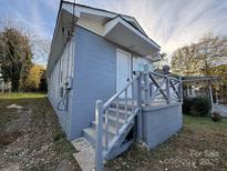 Charming home featuring a classic gray exterior, quaint front porch, and well-defined stairs leading to the entrance at 213 W Davidson Ave, Gastonia, NC 28052