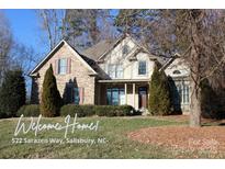 Charming two-story home boasts a stone facade, shuttered windows, manicured landscaping, and mature trees at 522 Sarazen Way, Salisbury, NC 28144