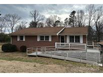 Charming brick home featuring an accessibility ramp, white trim, and mature landscaping on a cloudy day at 1215 S Myrtle School Rd, Gastonia, NC 28052