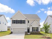 Charming two-story home features a modern design, manicured lawn, attached garage, and welcoming entrance at 122 Asmodean Ln, Troutman, NC 28166