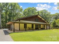 Inviting craftsman-style home with a sprawling covered porch and lush green lawn at 13124 Lemmond Dr, Matthews, NC 28105