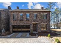 Charming two-story stone home featuring a glass garage door and manicured landscaping at 302 Ambleside Village Ln, Davidson, NC 28036