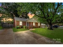 Charming brick home with lush green lawn and mature trees offering shade and curb appeal at 3714 Conway Ave, Charlotte, NC 28209