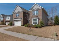 Two-story brick home showcasing a well-maintained lawn and attached two-car garage, offering curb appeal at 4856 Pepper Dr, Harrisburg, NC 28075
