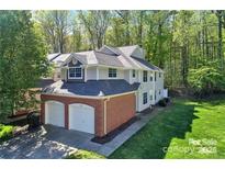 Two-story home features attached two-car garage, and a landscaped yard on a wooded lot at 5921 Amity Springs Dr, Charlotte, NC 28212
