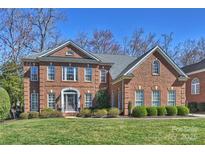 Beautiful two-story brick home with manicured lawn and mature trees on a sunny day at 9627 Baileywick Rd, Charlotte, NC 28277