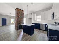 Modern open kitchen boasts an island and a unique brick column design feature, blending contemporary with rustic elements at 105 S York St, Lancaster, SC 29720