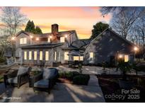 A large backyard features an outdoor dining and seating area with lush landscaping and exterior lighting at 107 Doris Ct, Lincolnton, NC 28092