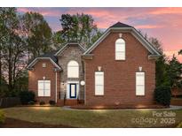 Beautiful brick and stone home with a manicured lawn and lush landscaping is bathed in the warm glow of the sunset at 109 Stirling Heights Ln, Fort Mill, SC 29715
