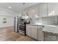 Modern kitchen with granite counters, stainless steel appliances, and gray subway tile backsplash at 1826 Taylor Ave, Charlotte, NC 28216