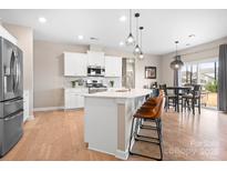 Bright kitchen featuring white cabinets, stainless steel appliances, and a spacious island with seating at 2024 Linn Cv, Waxhaw, NC 28173