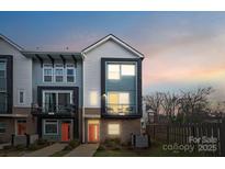 Modern townhome showcasing two stories, unique architecture, and a cozy second-floor balcony, all at dusk at 2132 Electric Ln, Charlotte, NC 28205