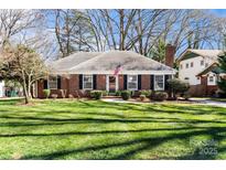 Charming single-story brick home featuring a well-manicured lawn and an American flag displayed on the front at 4425 Longwood Dr, Charlotte, NC 28209