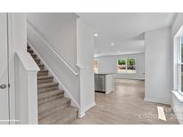Bright entryway featuring stairs with carpeted treads and white risers, leading to an open-concept living space at 1346 37Th Avenue Ne Ln, Hickory, NC 28601