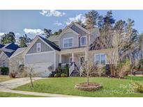 Beautiful two-story home with manicured lawn and classic architectural details under a partially cloudy sky at 17609 Caddy Ct, Charlotte, NC 28278