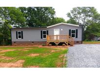 Charming single-story home with gray siding and a wooden front porch near a gravel driveway at 2013 Vick Wilson Rd, Shelby, NC 28152