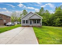 Charming home featuring a long driveway, inviting front porch, and beautiful landscaping at 117 Lippard St, Statesville, NC 28677