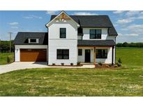 Charming two-story modern farmhouse with a well-manicured lawn and a welcoming, covered front porch at 1300 Austin Chaney Rd, Wingate, NC 28174