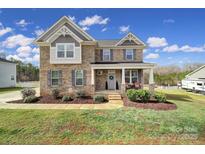 Charming two-story brick home featuring a welcoming front porch, landscaped yard, and beautiful architectural details at 2167 Whispering Winds Dr, Rock Hill, SC 29732