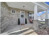 Inviting front porch featuring brick columns, a cozy sitting area, and a decorative wreath on the front door at 2167 Whispering Winds Dr, Rock Hill, SC 29732