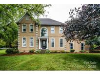 Stately two-story home with tan stucco, manicured lawn, and mature trees at 4825 1St Street Nw Ct, Hickory, NC 28601
