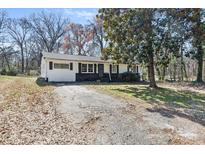 Charming single-story home with a white exterior, black shutters, and mature trees at 629 Johns Ln, Gastonia, NC 28052