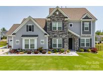 Charming two-story home featuring stone accents, a manicured lawn, and beautiful landscaping at 7133 Sumters Camp Trl, Fort Mill, SC 29707