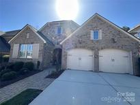 Charming brick home features a two-car garage, stone accents, and professionally landscaped front yard at 9218 Robbins Preserve Rd, Cornelius, NC 28031