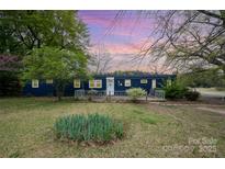 Charming home featuring a well-maintained lawn with mature trees and a cozy, inviting entrance at 9937 Harwood Ln, Charlotte, NC 28214