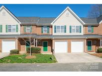 Charming brick townhouse featuring green shutters, a one car garage and a well-manicured lawn at 2021 Lennox Square Rd, Charlotte, NC 28210