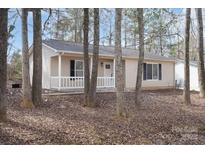 Charming single-story home with vinyl siding and a welcoming front porch surrounded by a wooded yard at 207 American Dr, Salisbury, NC 28147