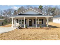 Charming single-story home features a covered front porch, gray siding, and manicured landscaping at 409 S Spargo St, Dallas, NC 28034